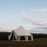 avalon bell tent placed on the grass outdoors with flaps opened and mesh closed